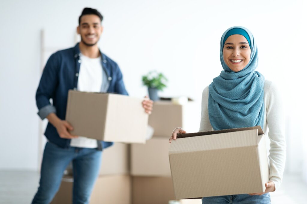 Happy muslim family holding moving supplies in their new apartment