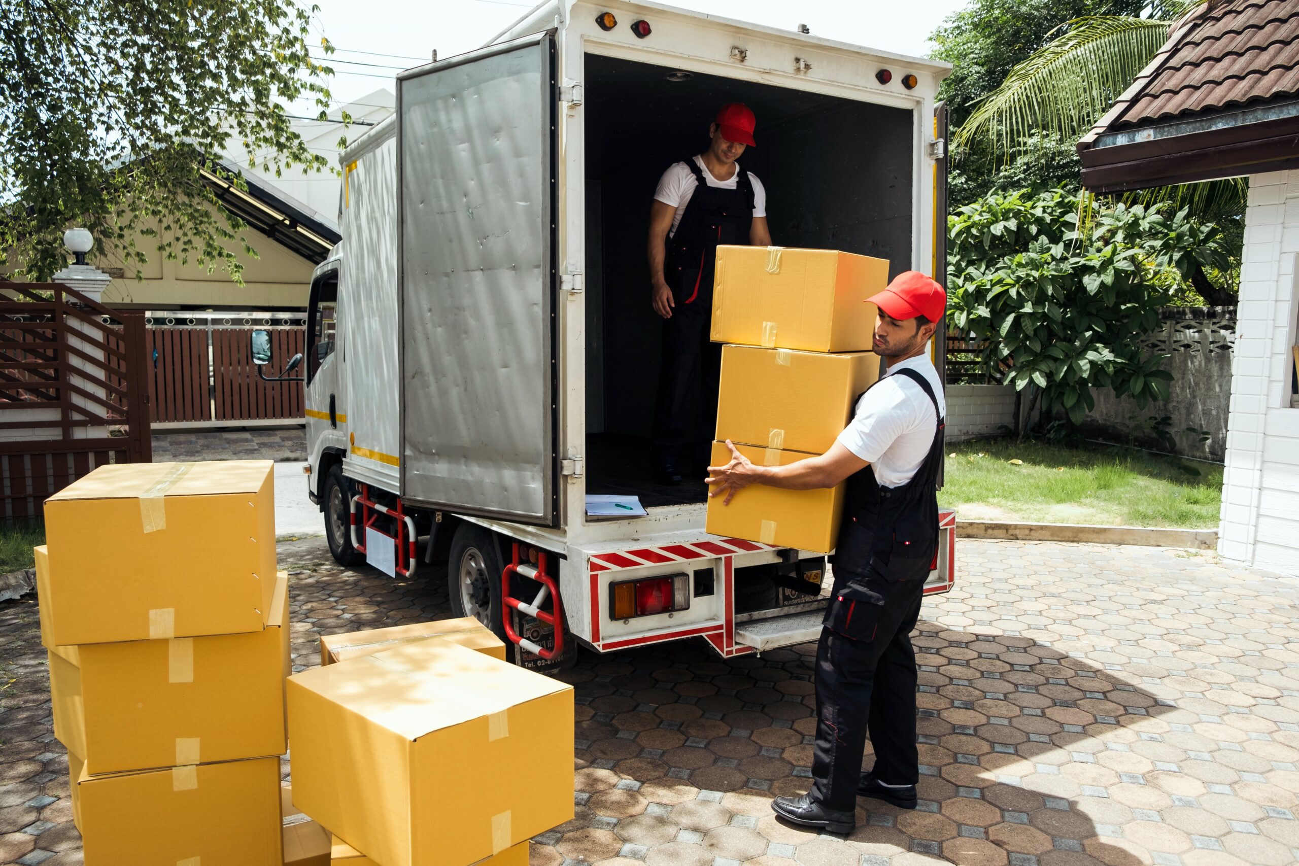 Asian,And,Caucasian,Workers,In,Uniform,Unloading,Cardboard,Boxes,From